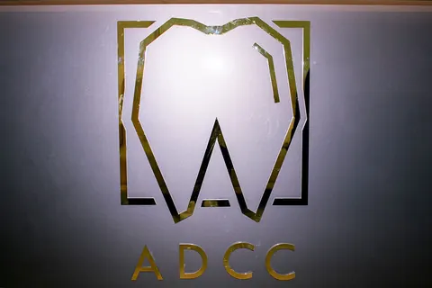The gold ADCC logo sign lit on a clinic wall