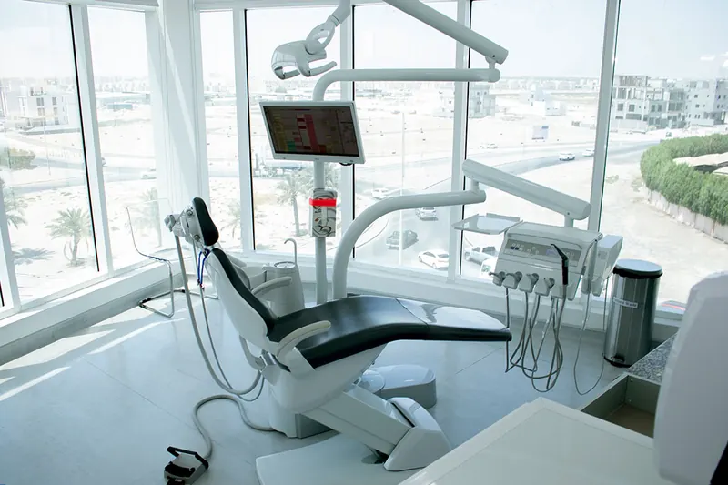 A treatment room at the clinic: a dental chair beside tall windows filled with daylight